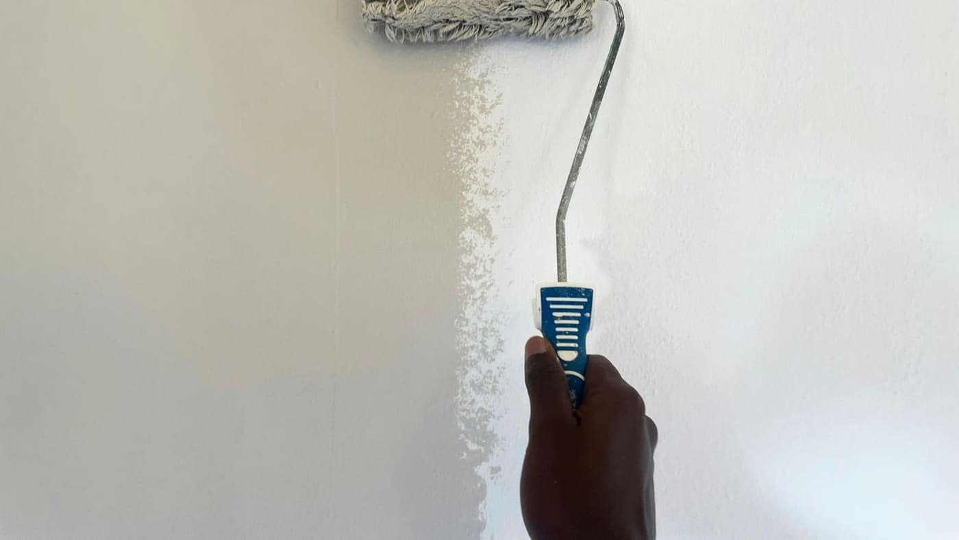 Rouleau appliquant une couche de peinture fraîche sur un mur