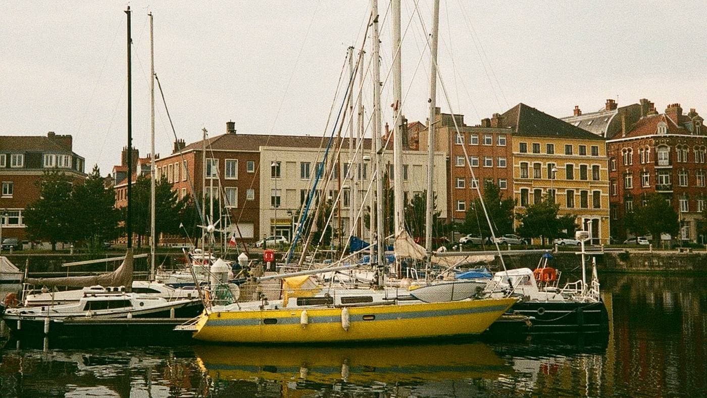 Port de plaisance avec voiliers amarrés, bâtiments colorés en arrière-plan
